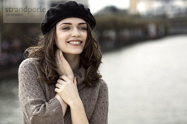 Porträt einer glücklichen jungen Frau mit Baskenmütze und Strickkleid