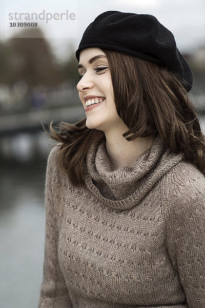 Porträt einer lächelnden jungen Frau mit Baskenmütze und Strickkleid