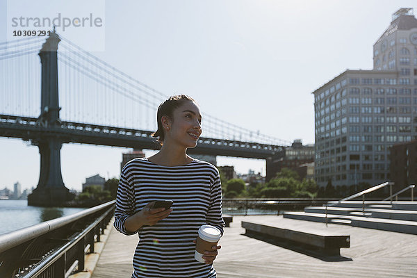 USA  New York City  Portrait der jungen Frau mit Smartphone und Kaffee zum Mitnehmen