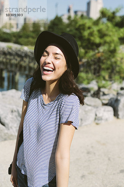 USA  New York City  Porträt einer lachenden jungen Frau mit schwarzem Hut