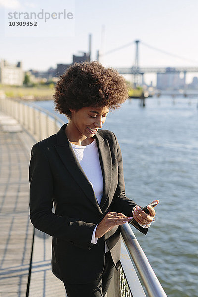 USA  New York City  lächelnde Geschäftsfrau mit Blick auf ihr Smartphone