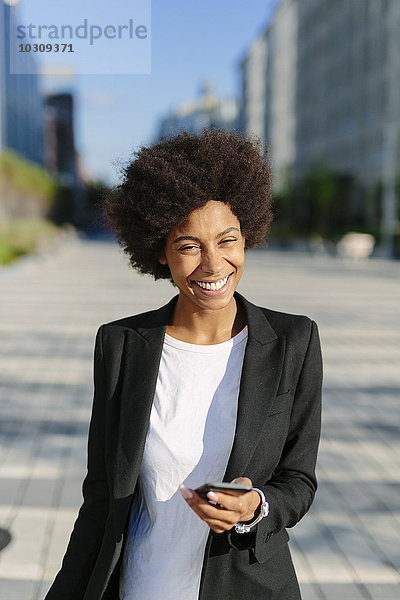 USA  New York City  Portrait einer lächelnden Geschäftsfrau mit Smartphone
