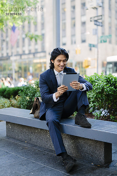 USA  New York City  Manhattan  lächelnder Geschäftsmann beim Betrachten des digitalen Tabletts