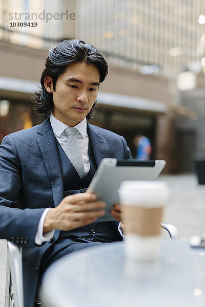 USA  New York City  Geschäftsmann im Outdoor-Café mit Blick auf das digitale Tablett