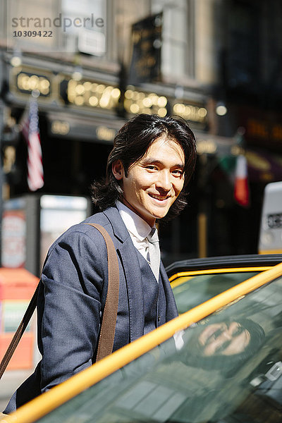 USA  New York City  lächelnder Geschäftsmann beim Einsteigen in ein Taxi