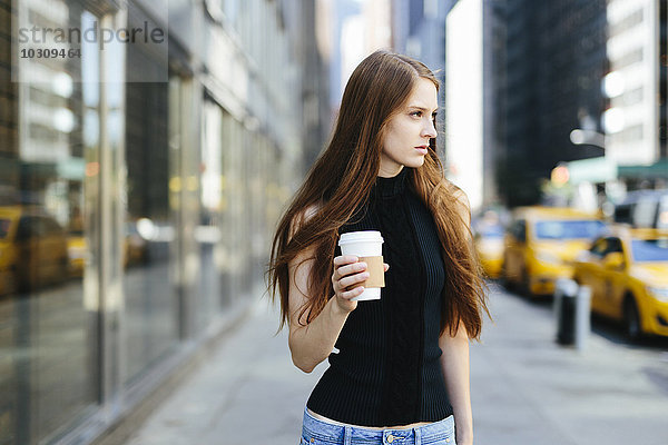 USA  New York City  Portrait einer jungen Frau mit Kaffee zum Mitnehmen