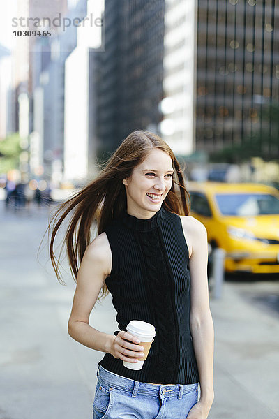 USA  New York City  Portrait der lachenden jungen Frau mit Kaffee zum Mitnehmen