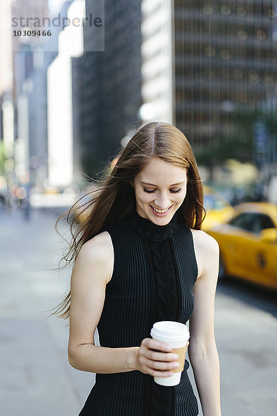 USA  New York City  Portrait einer lächelnden jungen Frau mit Kaffee zum Mitnehmen