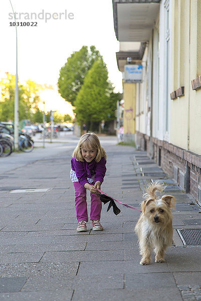 Kleines Mädchen auf dem Bürgersteig mit ihrem Hund