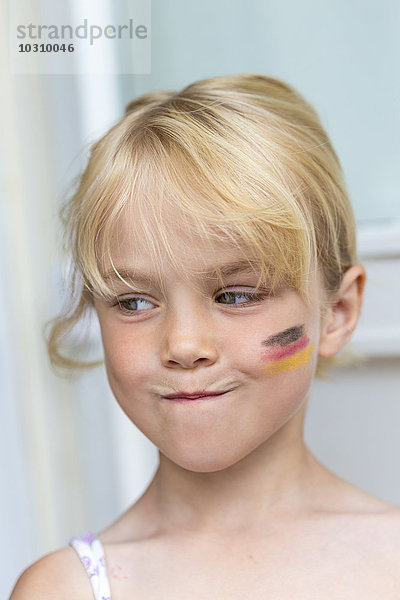 Porträt eines blonden Mädchens mit deutscher Flagge auf der Wange