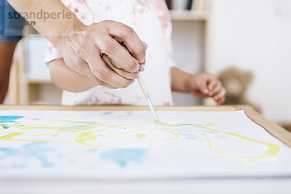 Frau hilft dem kleinen Jungen beim Malen mit Aquarellen  Nahaufnahme