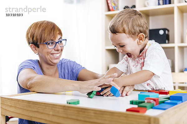 Porträt des kleinen Jungen und seiner Mutter beim Spielen mit Bausteinen