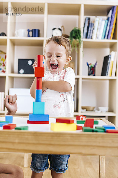 Porträt eines aufgeregten kleinen Jungen  der mit Bausteinen spielt.