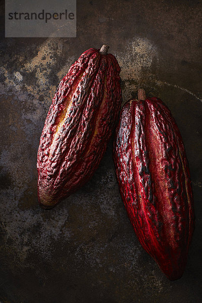 Zwei Kakaoschoten auf rostigem Grund