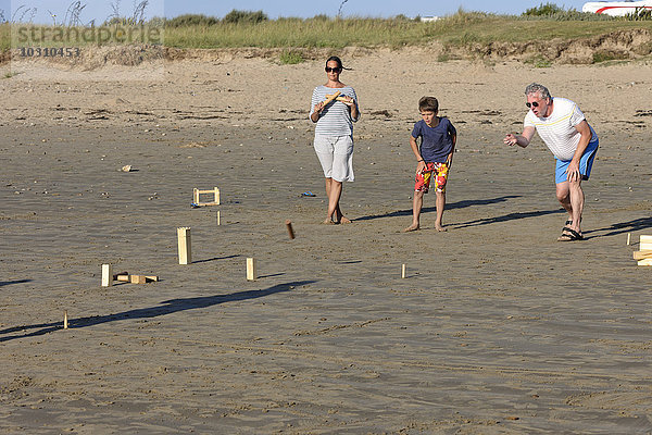 Eltern und Sohn spielen Kubb am Strand