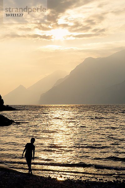 Italien  Veneto  Malcesine  Junge steht am Gardasee im Abendlicht