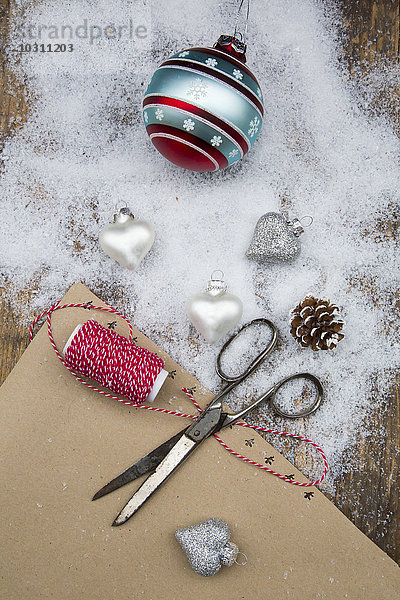 Weihnachtskugeln  Schere  Schnur  Packpapier und Kunstschnee