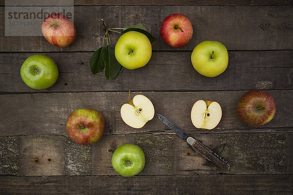 Verschiedene Äpfel und Taschenmesser auf Holz