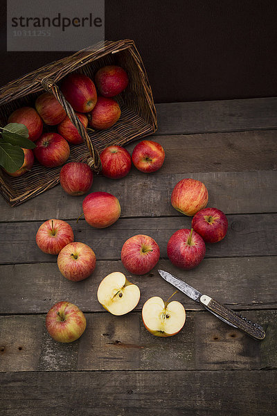 Rote Äpfel  Sortierung Gala  Korb und Taschenmesser auf Holz