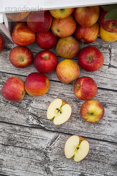 Ganze und geschnittene rote Äpfel auf Holz