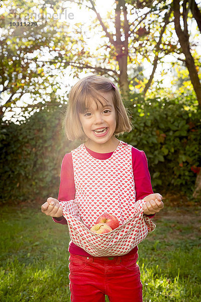 Porträt eines kleinen Mädchens mit Äpfeln in ihrem Kleid