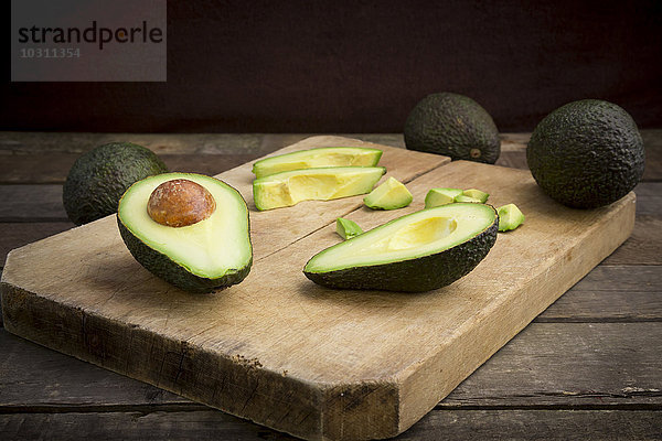 Ganze und geschnittene Avocado auf Holzplatte