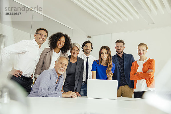 Portrait von lächelnden Geschäftsleuten mit Laptop im Konferenzraum