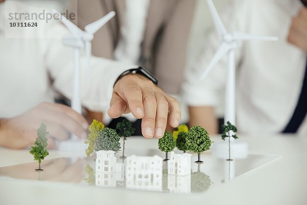 Nahaufnahme von Geschäftsleuten Windkraftanlagenmodell und Häusern auf Konferenztisch