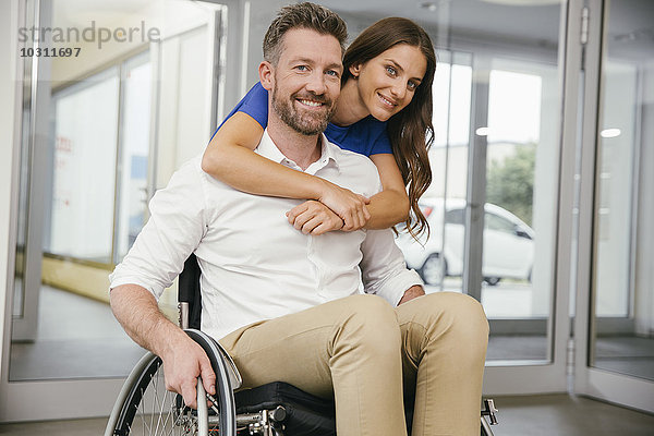 Mann im Rollstuhl mit seiner Freundin  glücklich umarmend