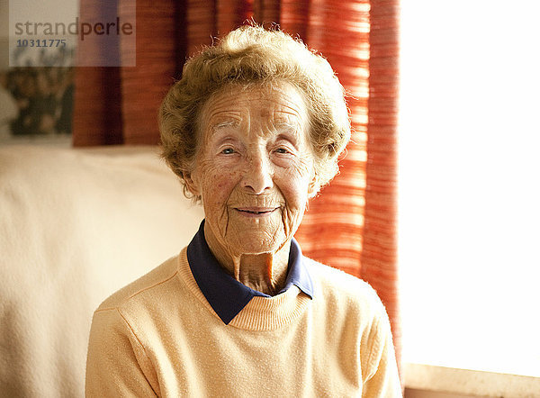 Porträt einer alten Frau  die auf einem Sessel in ihrem Wohnzimmer sitzt