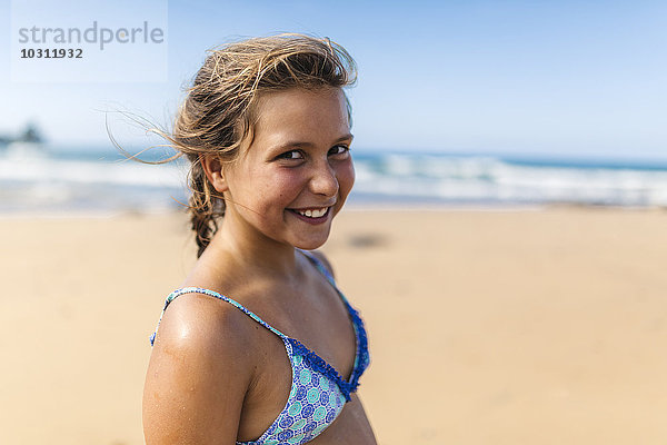 Porträt eines lächelnden Mädchens im Bikini-Top am Strand