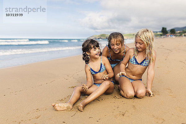 Spanien  Colunga  drei Mädchen am Strand sitzen und Spaß haben