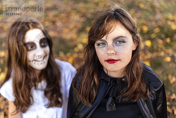 Porträt des Maskenmädchens an Halloween mit ihrer Freundin im Hintergrund