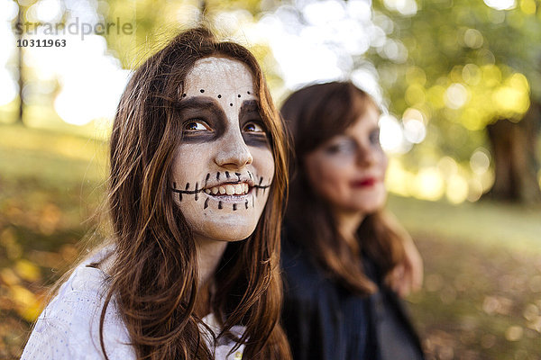 Porträt des Maskenmädchens an Halloween mit ihrer Freundin im Hintergrund