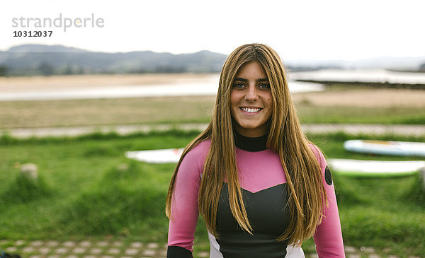 Spanien  Asturien  Villaviciosa  Portrait der lächelnden jungen Frau an der Küste