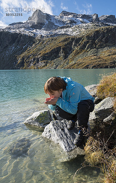 Österreich  Salzburger Land  Pinzgau  Frau am Trinkwasser vom Weisssee