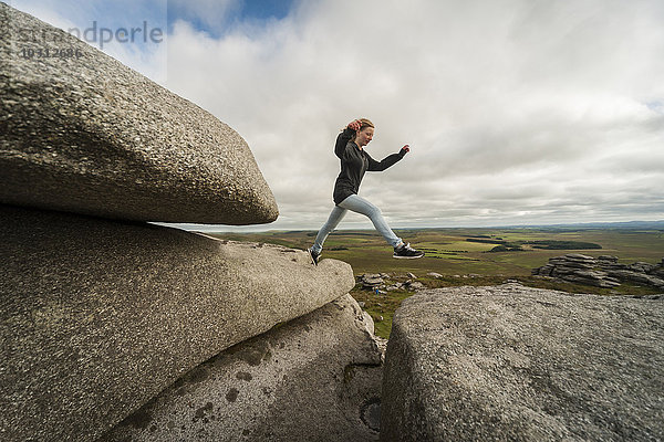 Vereinigtes Königreich  England  Cornwall  Bodmin Moor  Rough Tor  Rock Formation  Girl jumping