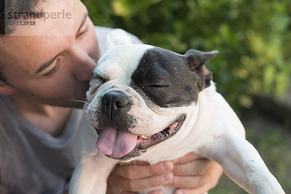Mann küsst seine französische Bulldogge