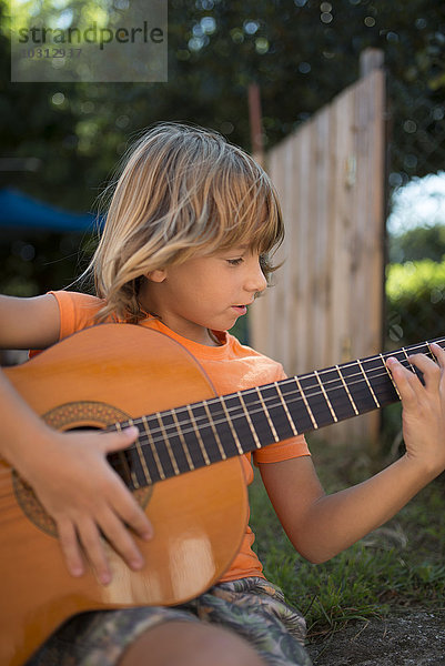 Spanien  Langhaariger blonder Junge spielt spanische Gitarre im Freien
