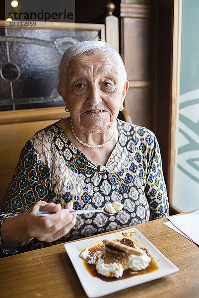 Seniorin isst Karamellpudding in einem Restaurant