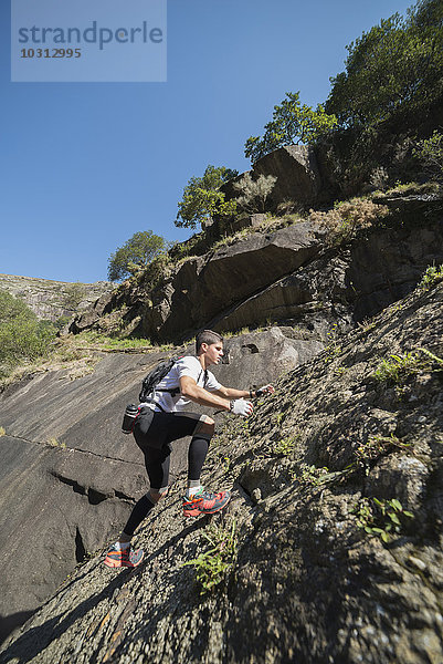 Spanien  Galizien  A Capela  Ultra Trail Runner auf einem Felshang