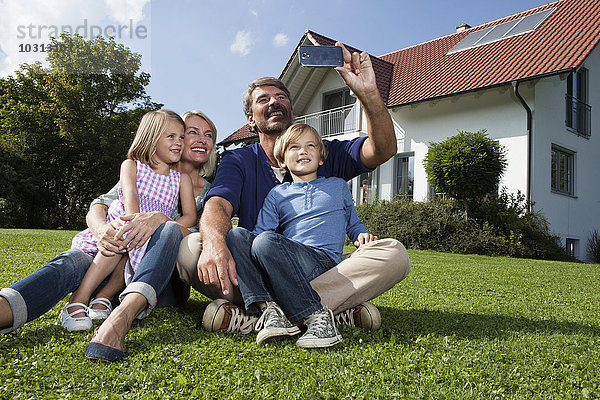 Glückliche Familie nimmt Selfie im Garten auf