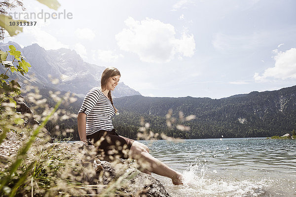Deutschland  Bayern  Eibsee  lächelnde Frau beim Spritzen im Wasser