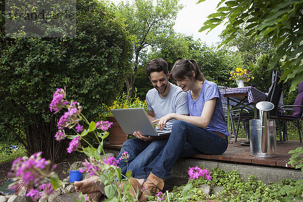 Glückliches Paar auf der Gartenterrasse mit Laptop