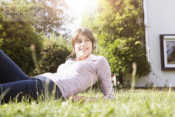 Lächelnde Frau im Garten liegend entspannt