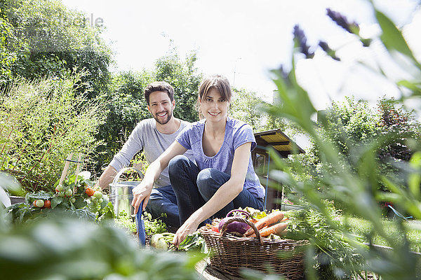 Lächelndes Paar beim Gärtnern im Gemüsebeet