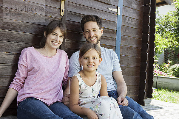 Porträt einer lächelnden Familie mit Tochter im Gartenhaus
