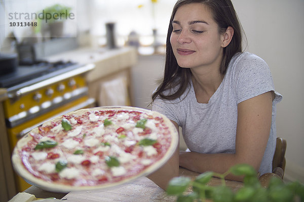 Junge Frau mit hausgemachter Pizza mit Mozzarella  Paprika und Basilikum