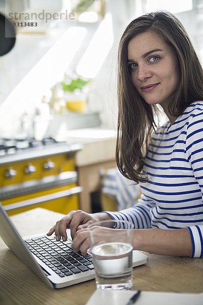 Junge Frau mit Laptop  die von zu Hause aus arbeitet