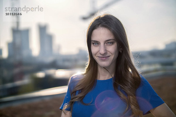 Deutschland  Frankfurt  Porträt einer lächelnden jungen Frau auf der Dachterrasse bei Gegenlicht